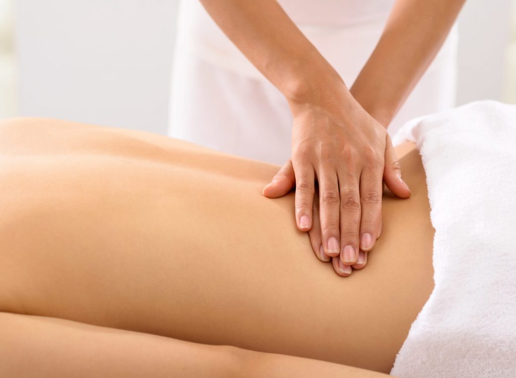 Hands of masseur massaging female back